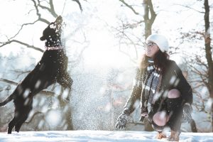 Frauchen und Hund im Schnee - da sollte man auf die Pfotenpflege wert legen